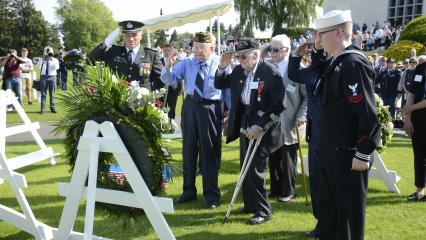 Men salute after laying a wreath.