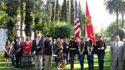 Men and women in uniform march with flags or firearms as part of the Honor Guard.