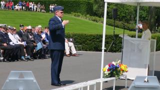 Man in uniform salutes after laying a wreath. 